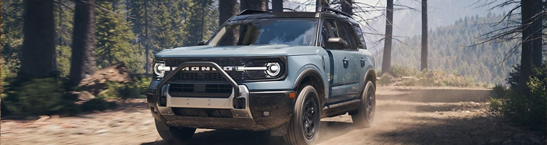 A Ford Bronco driving off-road through a wooded area
